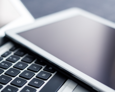 An open laptop with an iPad laying on the keyboard.