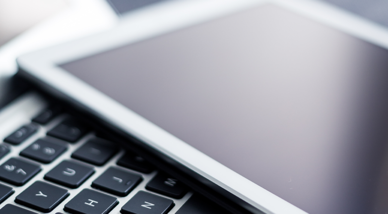 An open laptop with an iPad laying on the keyboard.